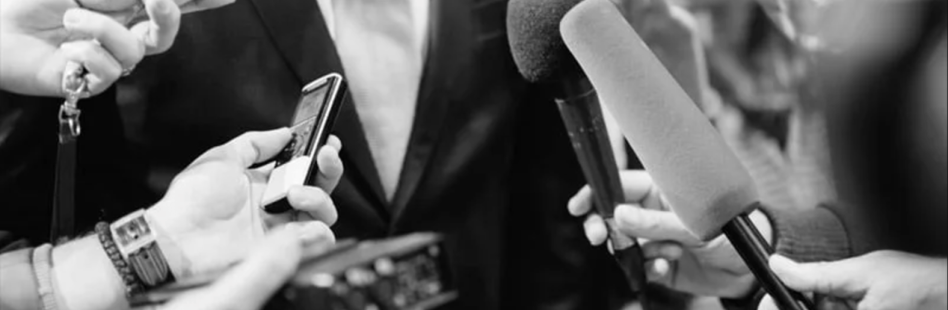 Photo noir et blanc de micros tendus vers quelqu'un dont on ne voit pas le visage