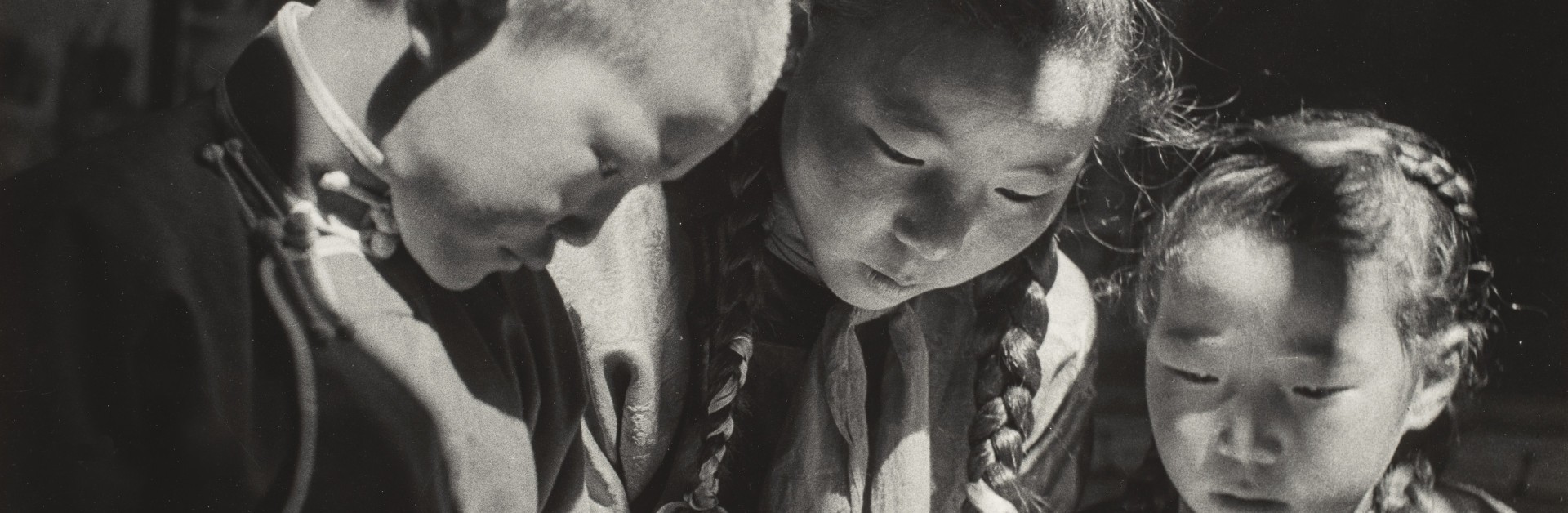 Trois enfants regardent un livre et font leurs devoirs d'école