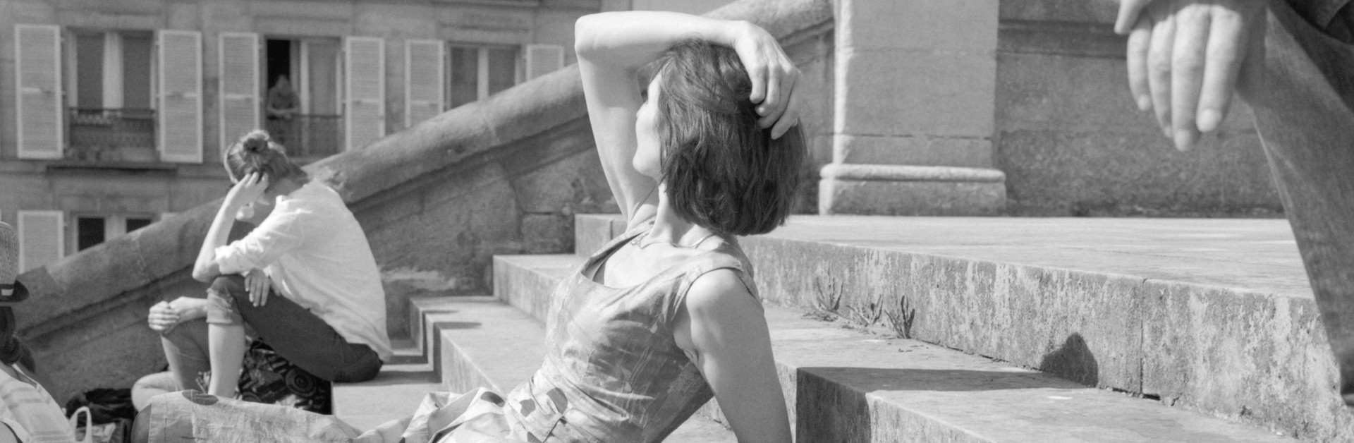 Femme assise sur des marches d'escalier en extérieur profite du soleil
