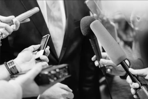 Photo noir et blanc de micros tendus vers quelqu'un dont on ne voit pas le visage